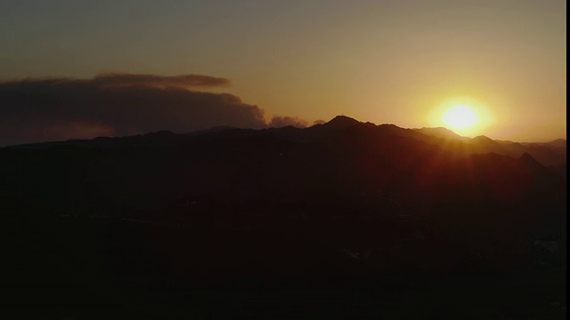 静止的画面，马里布山脉，金色的夕阳刚刚在山脊上，烟从远处的灌木丛火从远处的山峰后面滚滚升起视频素材