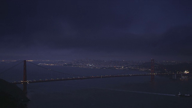 的夜晚。完整跨度的金门大桥在前景，旧金山在背景视频素材