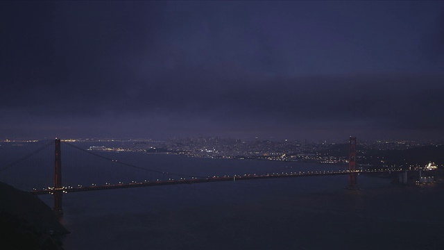 的夜晚。完整跨度的金门大桥在前景，旧金山在背景视频素材