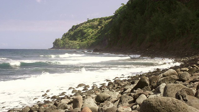 在遥远的美国夏威夷考艾岛，小海浪冲击着岩石海滩和山脉视频素材