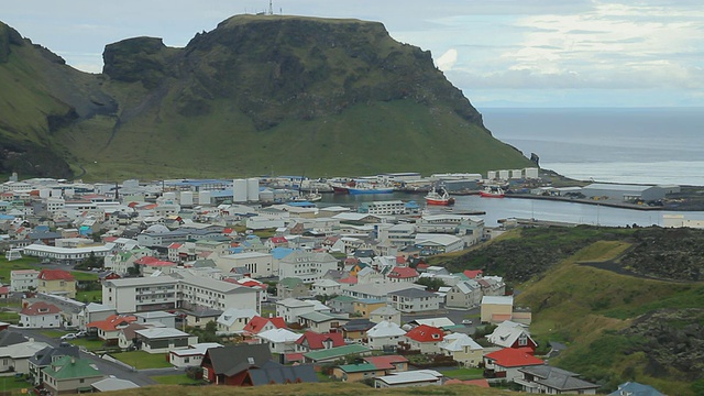 在冰岛Sudhurland vestmannaeyjar, vestmannaeyjar下山谷中有建筑的船只抵达vestmannaeyjar岛港口视频素材