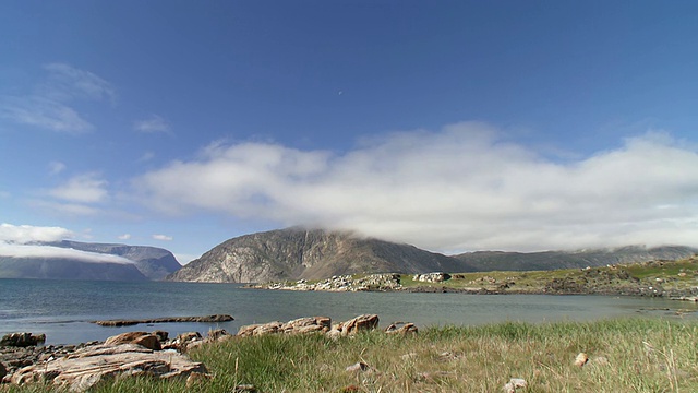 平静的海水与云覆盖山顶和草地岩石覆盖地面/托加Mtns，拉布拉多，加拿大视频素材