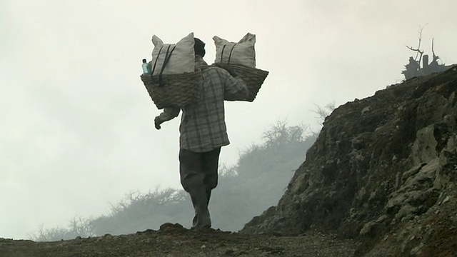 在印度尼西亚爪哇岛伊真火山采矿的男子携带硫磺视频素材