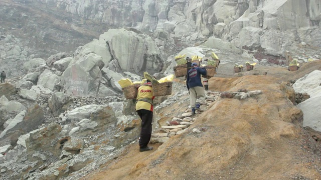 印度尼西亚爪哇伊真火山的矿工携带固体硫磺爬上了伊真火山口视频素材