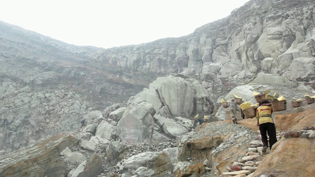 印度尼西亚爪哇伊真火山的矿工携带固体硫磺爬上了伊真火山口视频素材