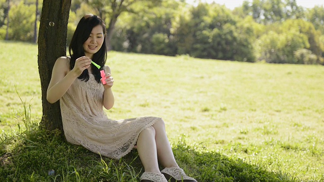 女士在树下玩肥皂泡的照片/宇次，日本京都视频素材