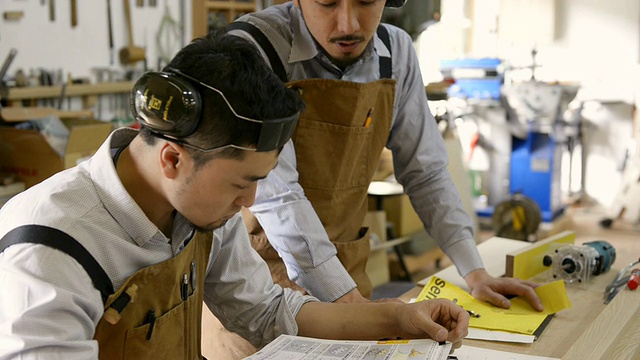 日本京都，两名木工在自己的工作台上看书的照片视频素材