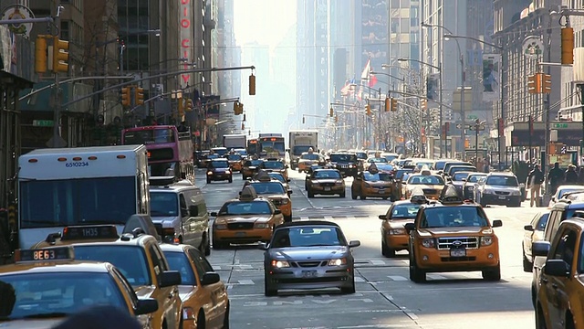 美国纽约，第六大道上行驶的汽车，穿过交通拥挤的人行横道的行人和摩天大楼视频素材