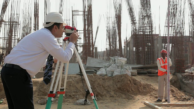 建筑师通过经纬仪在建筑工地，德里，印度视频素材