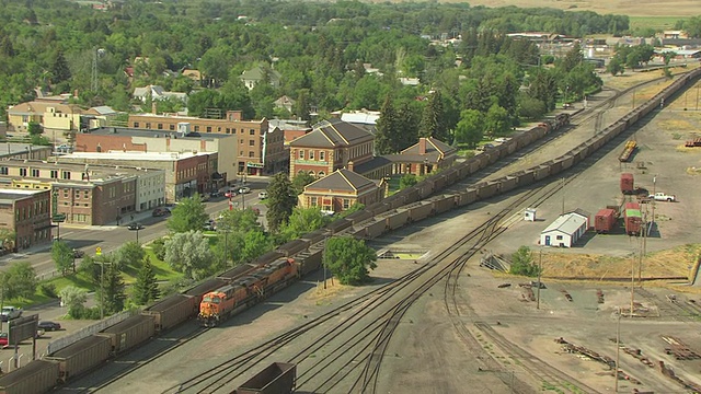 WS AERIAL DS View over BNSF train on tracks by downtown buildings with mountains /利文斯顿，蒙大拿，美国视频素材