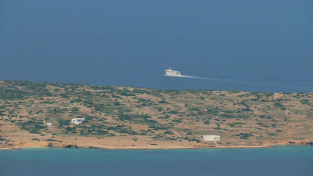 航拍的渡轮在海洋中移动和两个房子在岛上/ Cyclades，希腊视频素材