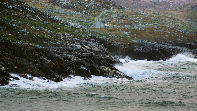 英国苏格兰刘易斯岛，激动的海浪拍打着岩石海岸，背景是房子视频素材