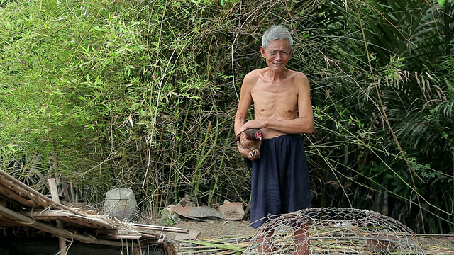 一位老人拿着鸡肉微笑的照片/越南龙安视频素材