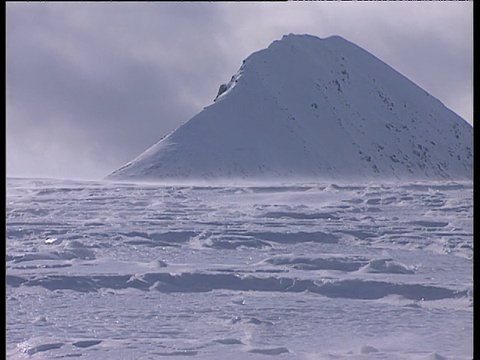 在斯瓦尔巴特群岛的背景中，雪吹过冰雪覆盖的山脉视频素材