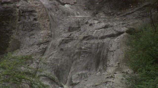 水从温泉池附近的悬崖上涓涓而下。高清。视频素材