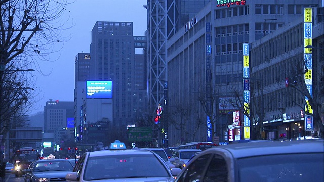 在首尔，交通沿着繁忙的城市街道经过高楼大厦。高清。视频素材