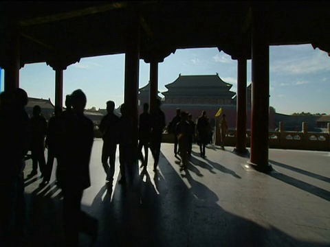 在北京紫禁城的背景下，游客的剪影在寺庙内、蓝天和其他寺庙周围徘徊视频素材