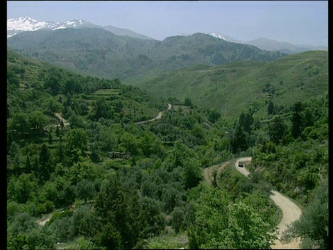 绿色景观和山谷与雪山在背景pan右边绿色山谷和4X4沿着道路克里特岛视频素材