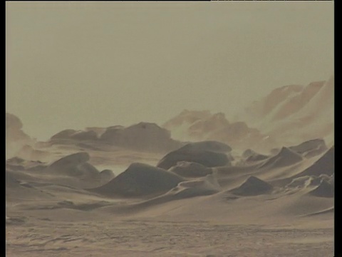 暴风雪在被雪覆盖的土地和山脉上翻腾视频素材