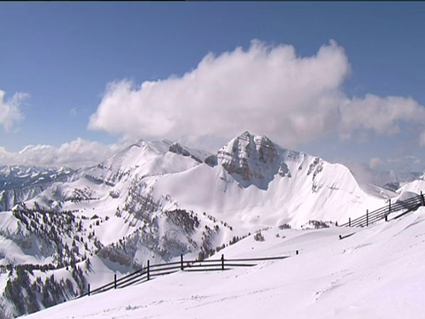 有围栏的滑雪坡道和白雪覆盖的山峰在蓬松的云下视频素材