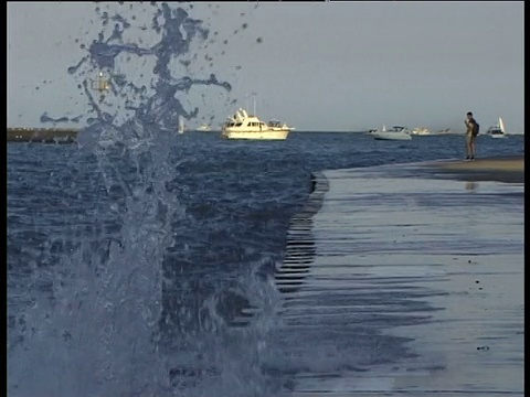 波浪溅过齿边码头，人站在边缘系泊的船在水的背景视频素材