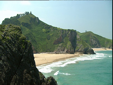 沙湾与海浪拍打海岸从浅绿色的海洋大苔藓覆盖悬崖在背景视频素材