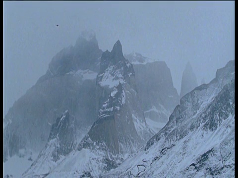 大风把雪吹过雾蒙蒙的山峰视频素材