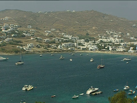 豪华游艇停泊在米科诺斯湾(Mykonos Bay)，背景是山坡上粉刷成白色的公寓视频素材