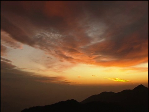 夕阳西下，令人惊叹的山脉被粉色和橙色的棉花糖云包裹着视频素材