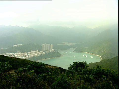 潘文石离开海湾和离岛，翻山越岭，来到另一个海湾，高楼大厦建在香港的山坡上视频素材