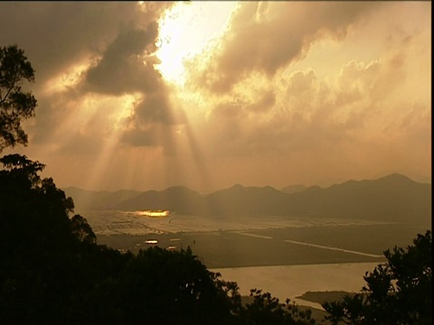 太阳穿过云层，笼罩在中国群山包围的水田上视频素材