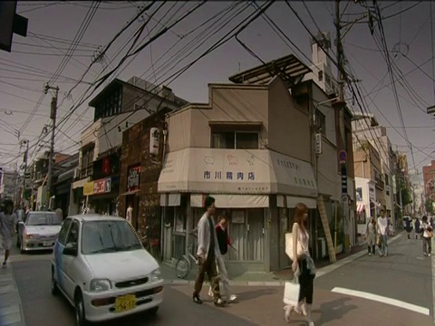 交通和行人在福冈狭窄的街道上穿行，街道下面是杂乱的电报线视频素材