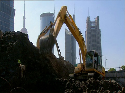 机械挖掘机在以上海为背景的东方明珠塔和其他摩天大楼建筑工地上挖洞视频素材