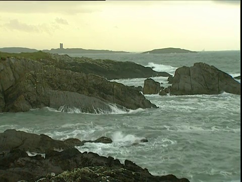 海浪拍打着苏格兰远处的岩石海岸城堡视频素材