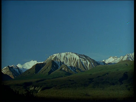 月亮穿过夜空，然后太阳升起露出山脉，育空视频素材