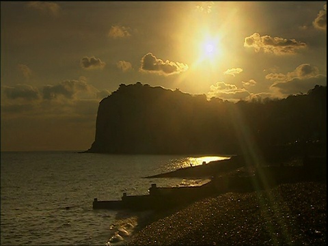 夕阳落在悬崖上，海浪拍打着肯特卵石滩视频素材