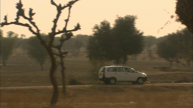 Pan right as car travels through arid landscape高清版视频素材