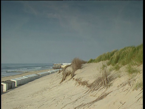 宁静的海滩景色包括海滩小屋和翻滚的大海;荷兰视频素材