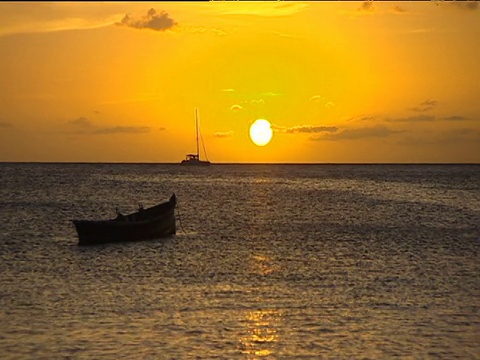 金色的日落在波光粼粼的海面上，船的轮廓漂浮在前景圣卢西亚视频素材