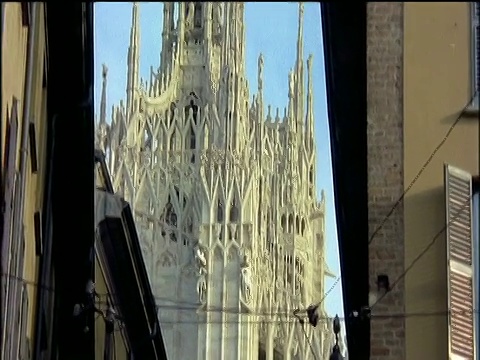 从两座较小的建筑之间的紧密视野，向上倾斜米兰大教堂(Duomo)的外部视频素材