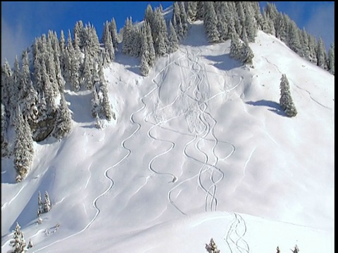 从山坡上滑雪者的锯齿形雪道上缩小镜头。视频素材