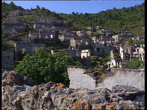 潘就在山坡上的废弃村庄石屋上视频素材