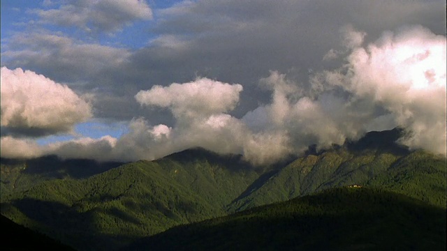 滚滚的白云侵袭着郁郁葱葱的青山。高清。视频素材