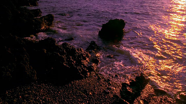 倾斜从海浪拍击岩石到棕榈树在日落的太平洋海岸，夏威夷。视频素材