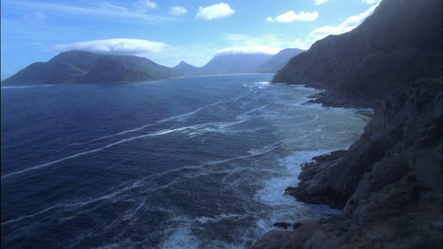 沿着蜿蜒的海岸公路向前追踪，下面有大海和岩石，开普敦。视频素材