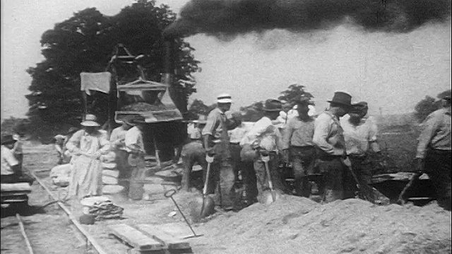 在背景(道路建设)/纪录片中，1910年代穿着工装裤的人用铲子/大型机器工作视频素材