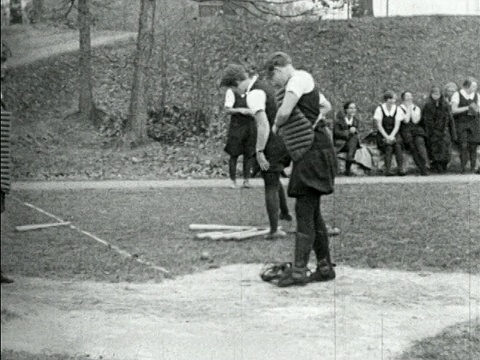 B/W 1920年代的女孩在户外的女孩棒球比赛中交换捕手的装备视频素材