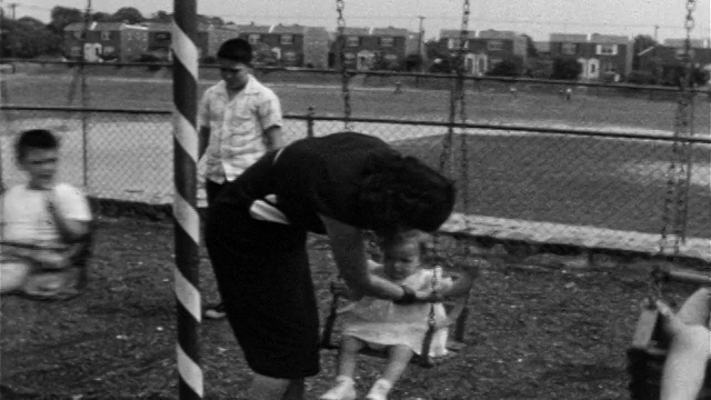 1955年，潘女士将不情愿的小女孩从秋千上抬起来，把她转移到婴儿车/菲拉。视频素材