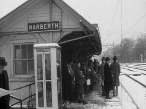 1955年，戴着帽子和外套的男男女女在白雪覆盖的站台上等着“NARBERTH”标志视频素材