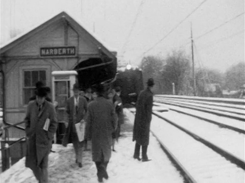 1955年的火车抵达标有“NARBERTH”的雪车站台/人们在站台上行走视频素材